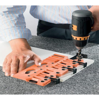 Blum Drilling And Marking Jig For Box Systems 2 a man using a drill to drill a piece of wood